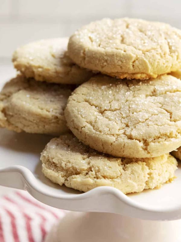 Almond Flour Sugar Cookies stacked on a white cake plate