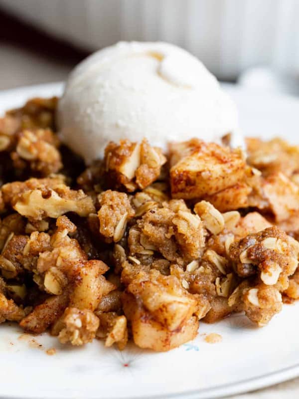 Apple Crisp served on a white plate with a scoop of vanilla ice cream.