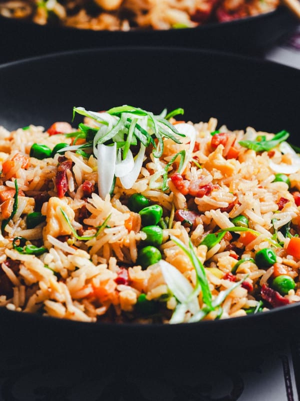 Bacon Fried Rice served in a black bowl and photographed at an angle.