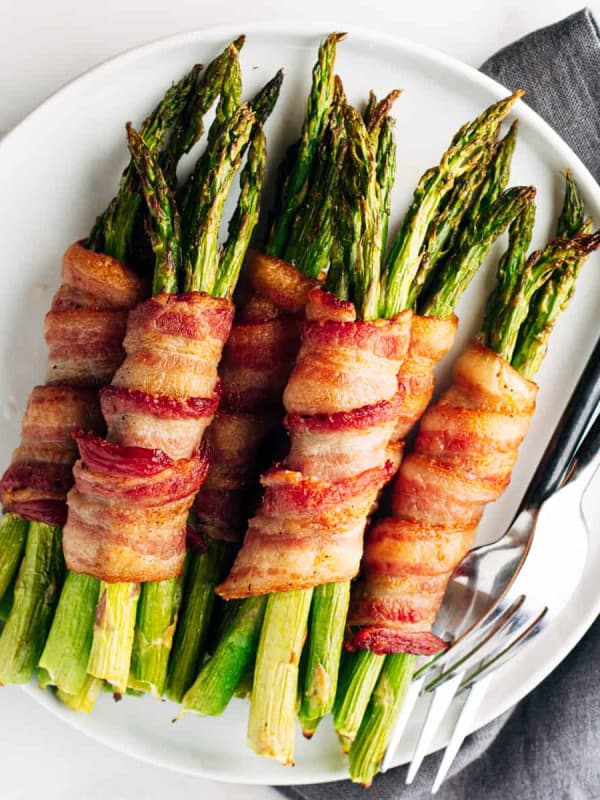 bacon wrapped asparagus served on a round white platter and photographed from above.