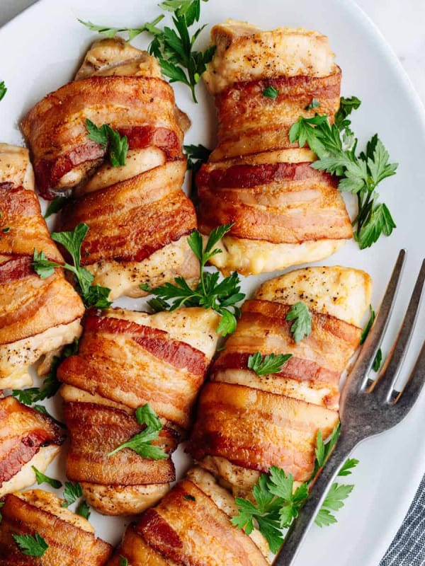 Bacon Wrapped Chicken Thighs served on a white oval platter photographed from above.