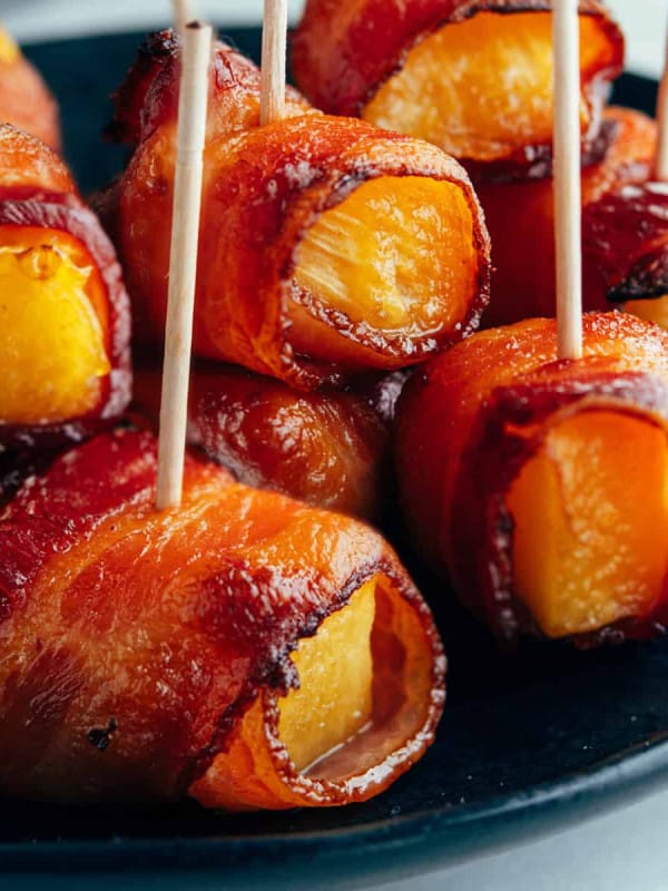 Bacon Wrapped Pineapple on a black plate.