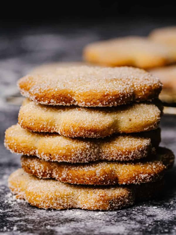 Biscochitos stacked on a gray granite surface.