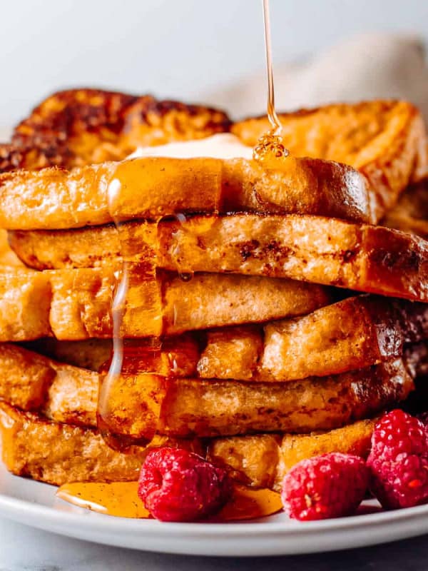 pouring syrup on stack of Brioche French Toast.