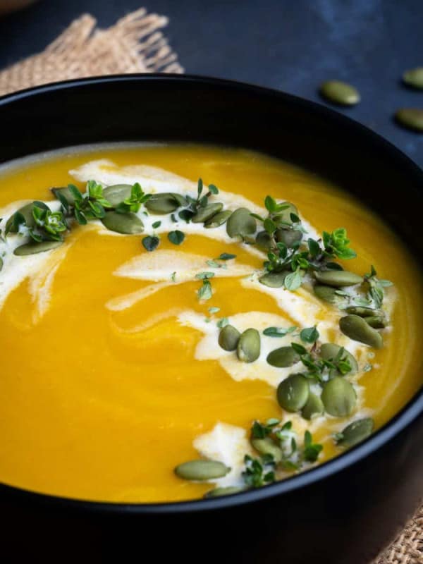 Butternut Squash Bisque served in a black bowl and photographed at an angle.