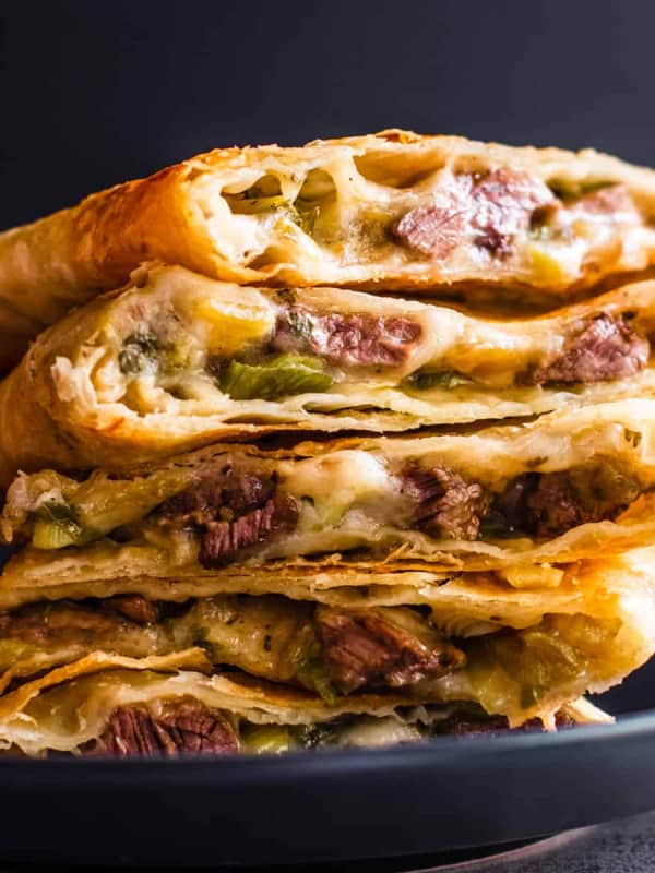 Carne Asada Quesadilla wedges stacked on a black plate.