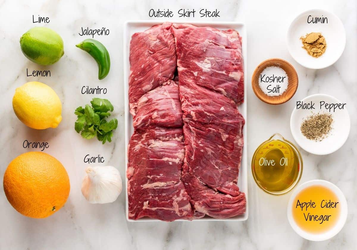 Carne Asada in the oven Ingredients on a white marble board.