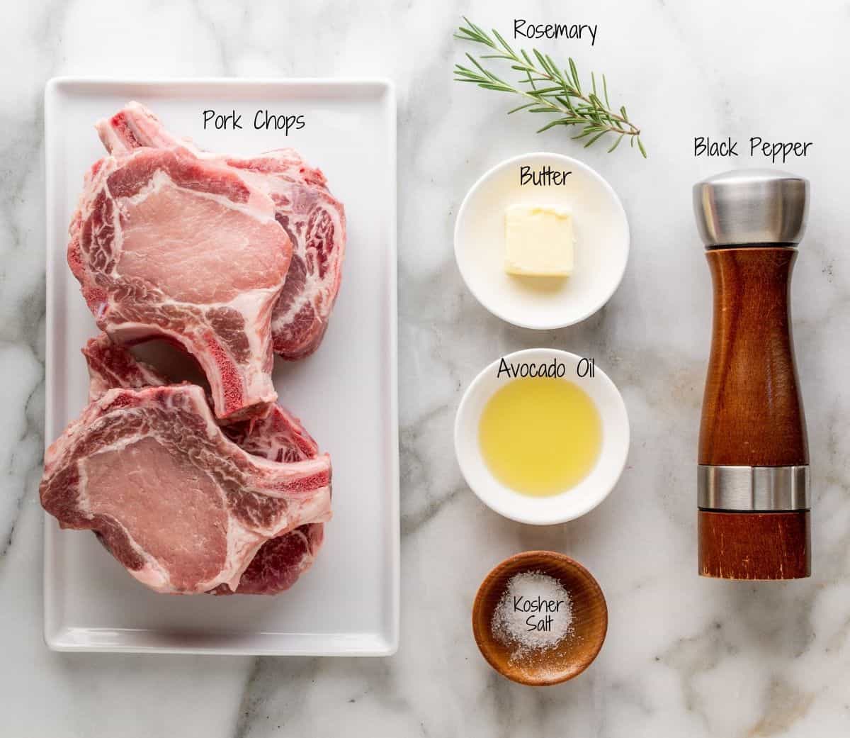 Cast Iron Pork Chops Ingredients on a white marble board.