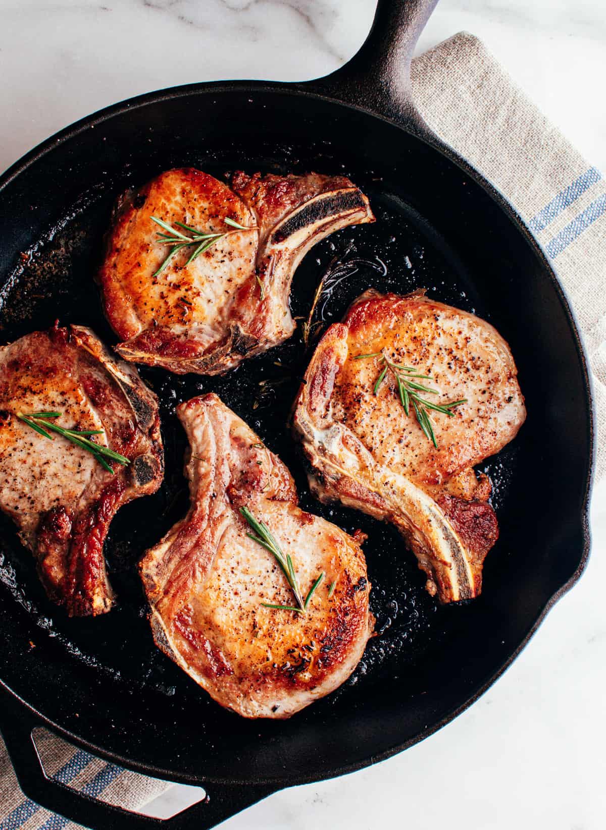 seared pork chops in a cast iron pan photographed from above.