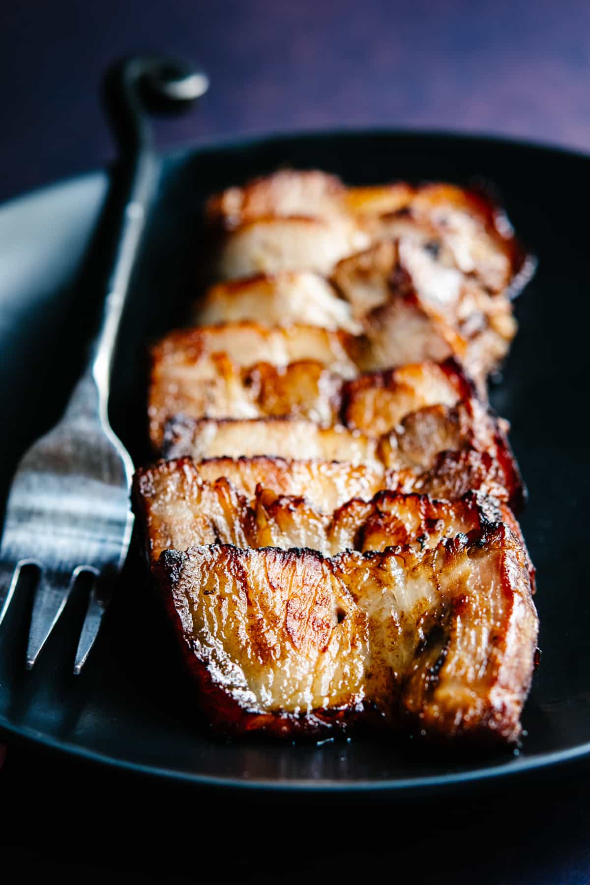 Chashu Pork served on a black plate with a serving fork