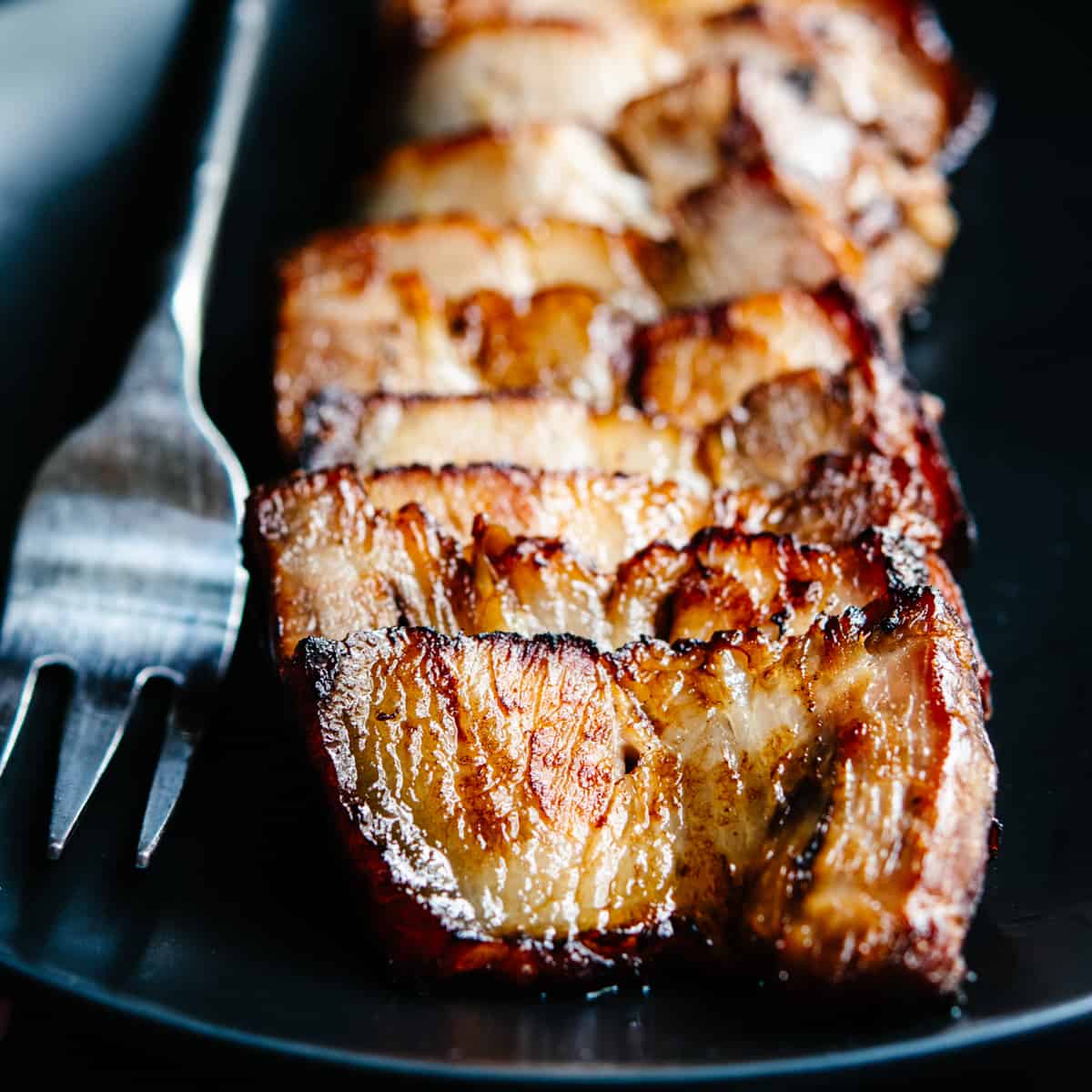 Chashu Pork served on a black plate with a serving fork