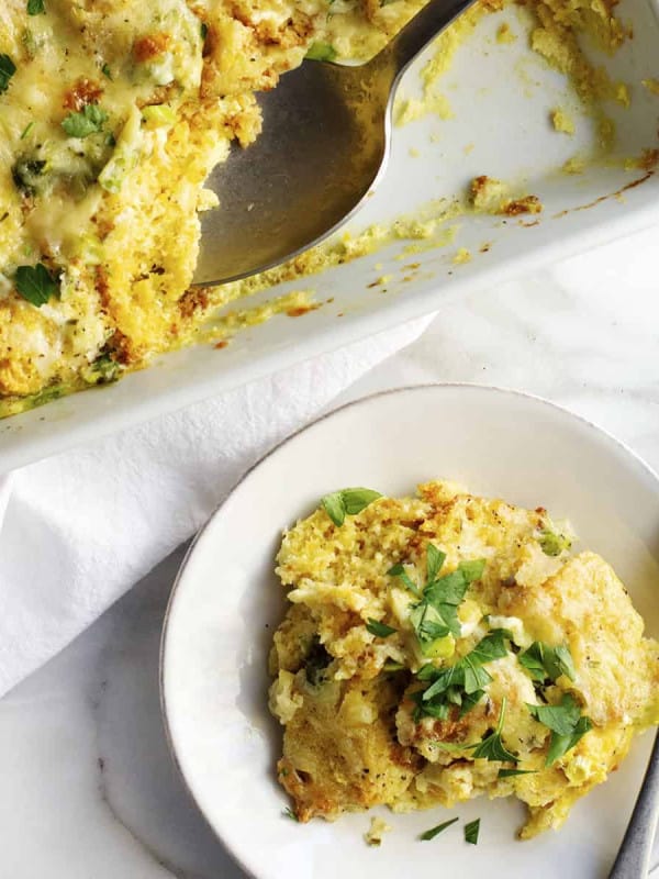 Cornbread Pudding served in a white casserole dish with a serving on a small plate beside