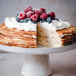 Crepe Cake served on a white ceramic cake plate with one slice cut out.