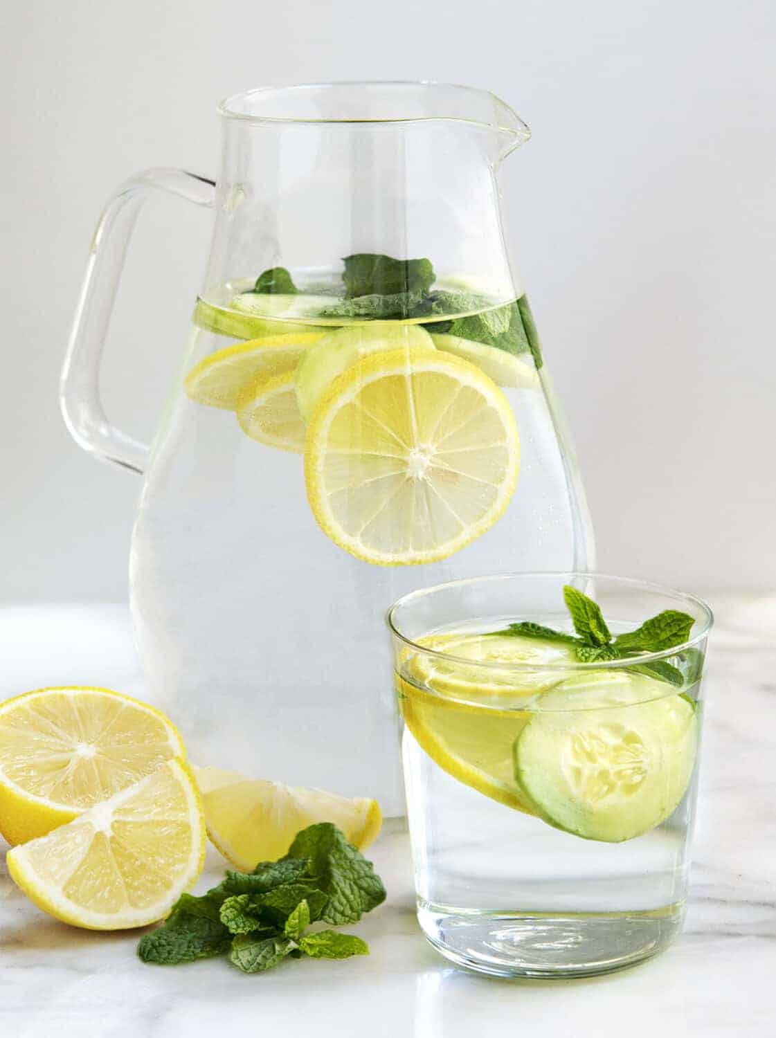 Cucumber Lemon Mint Water in a glass pitcher and a glass tumbler