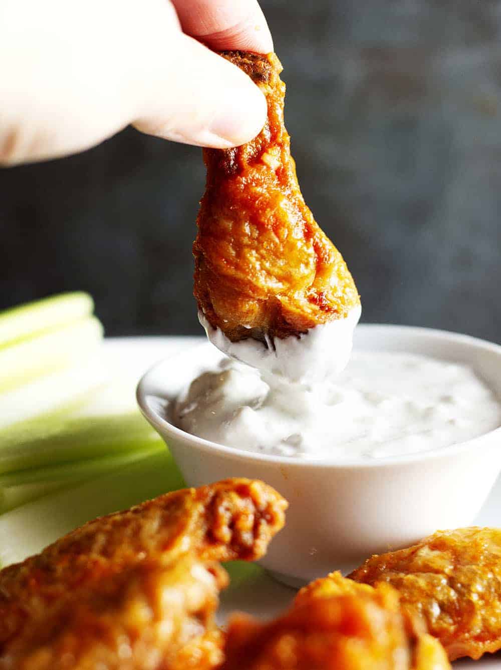 Dipping Crispy Baked Buffalo Wings in blue cheese dressing