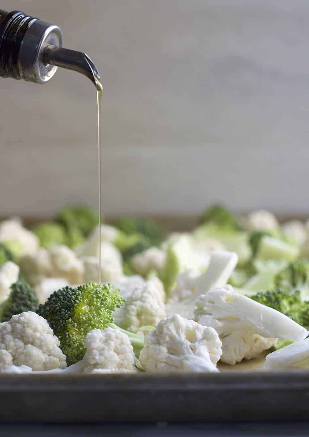 Drizzling Olive Oil on raw Broccoli and Cauliflower