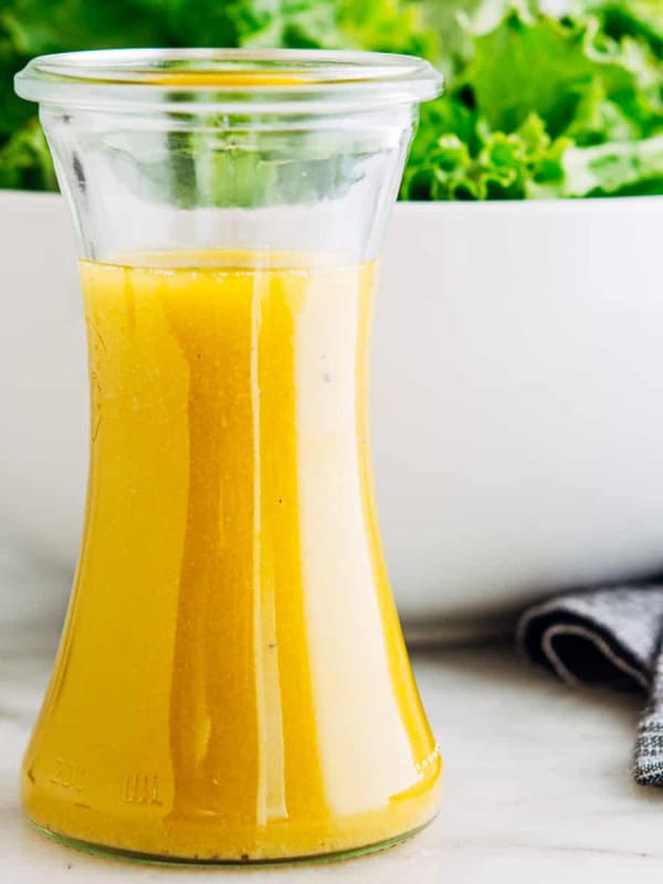 French Vinaigrette served in a small carafe with a green salad behind.