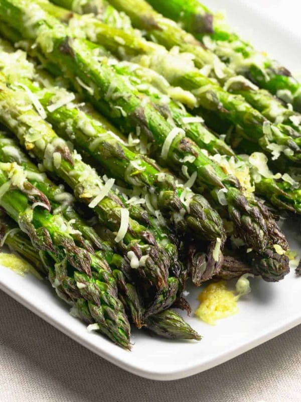 Garlic Parmesan Asparagus served on a white rectangular platter and photographed close up from an angle.