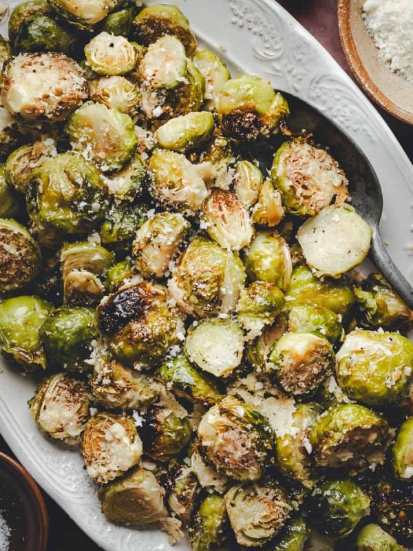 Close up shot of Garlic Parmesan Brussels Sprouts served on a white oval platter and photographed from the top.