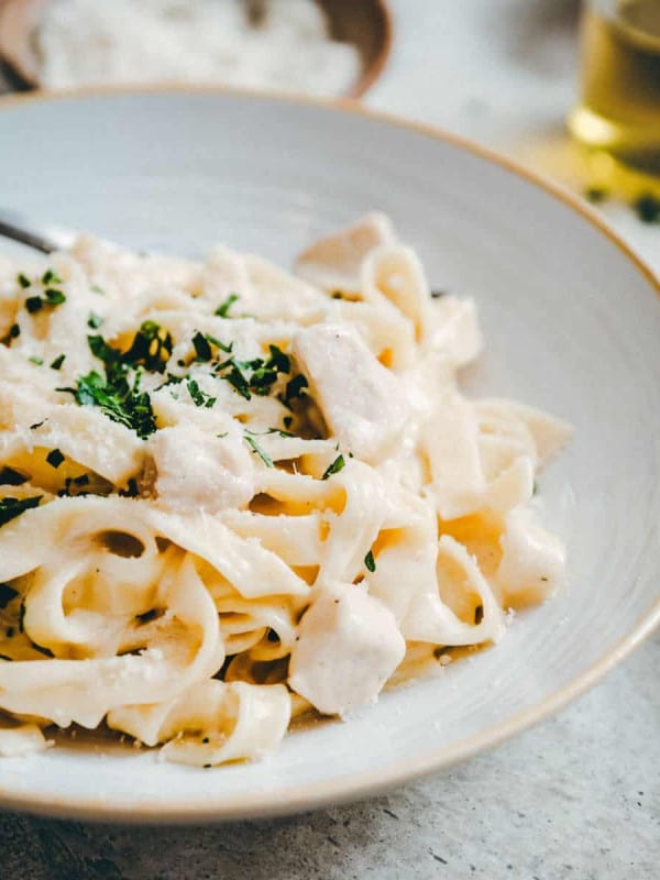 Garlic Parmesan Chicken Pasta served in a white ceramic bowl photographed at an angle.