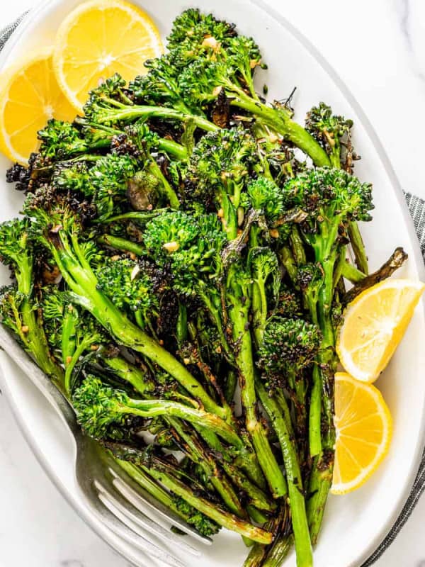 grilled broccolini on a white oval platter photographed from above.