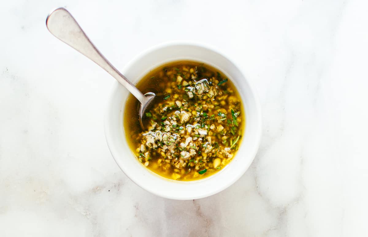 Grilled Lamb Chops marinade in a white bowl with a spoon.