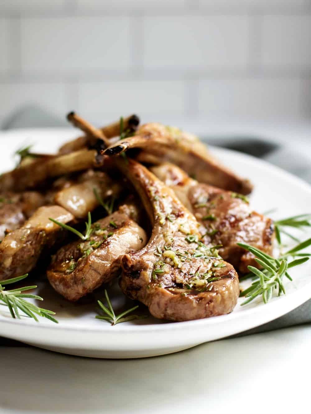 Grilled Lamb Chops on a white platter with rosemary sprigs