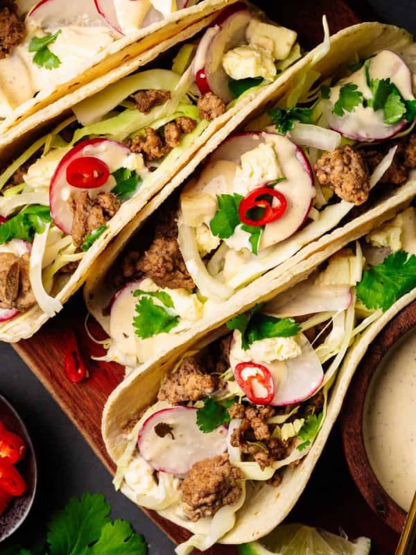 Ground Pork Tacos served on a wooden board and photographed from the top.