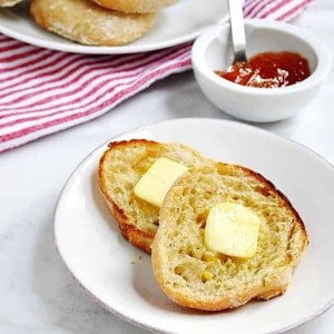 Homemade-English-Muffins-topped-with-Melting-Butter served on white plates featured