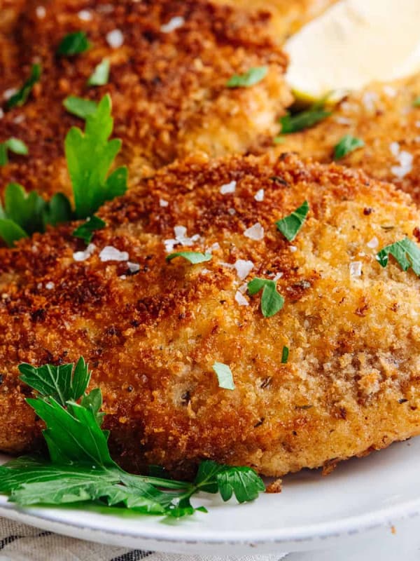 Italian chicken cutlets served on a white oval platter.