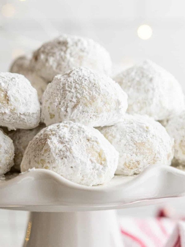 Italian wedding cookies stacked on a white ceramic cake stand.