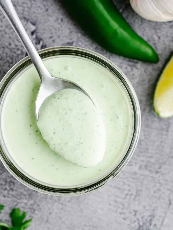 Spooning jalapeno Ranch Dressing out of a glass jar.