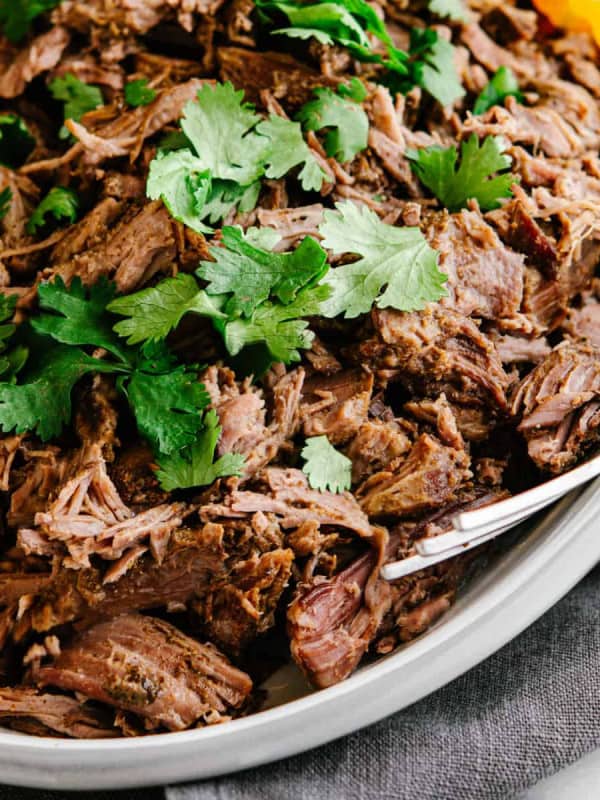 shredded lamb barbacoa served on an oval platter.