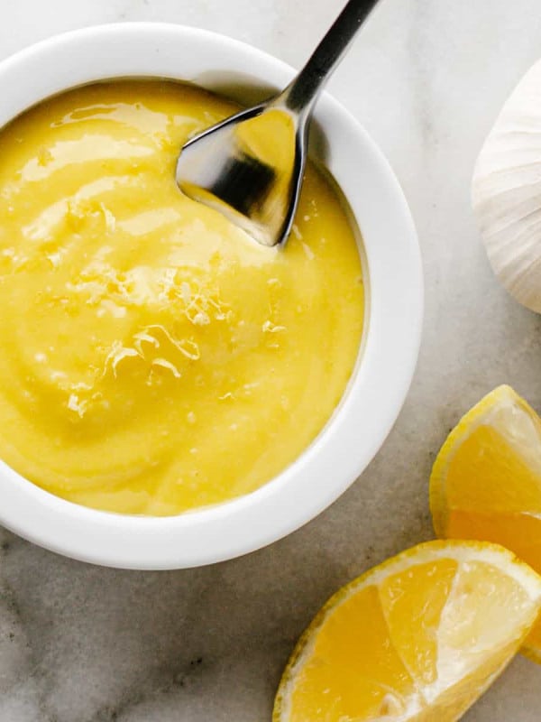 Lemon Garlic Aioli served in a small white bowl with a spoon photographed from above.