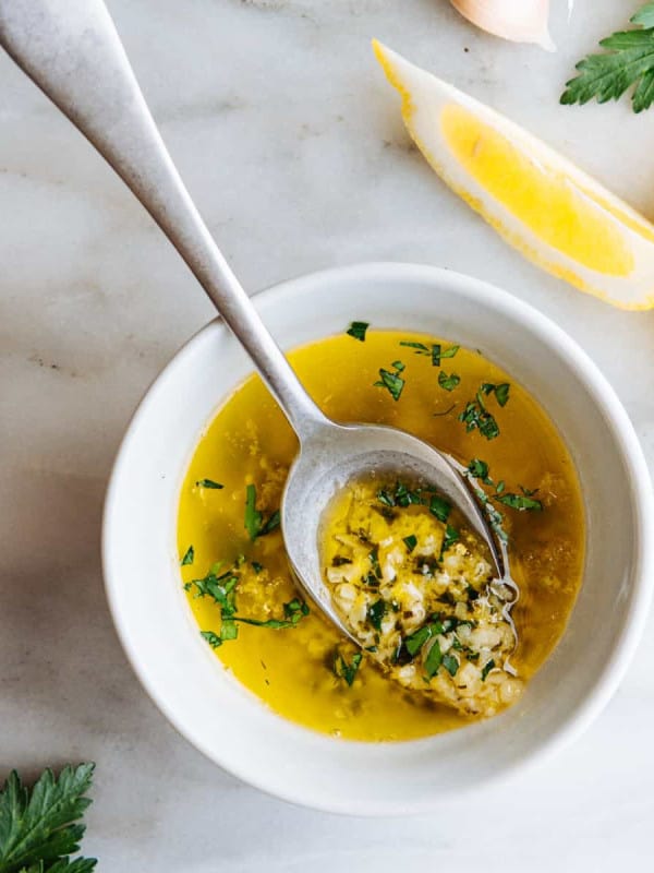 Lemon Garlic Butter Sauce served in a white bowl with a serving spoon on a white marble board