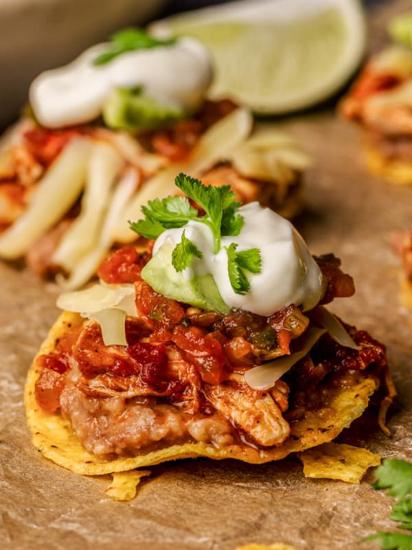 Close up photo of Mini Chicken Tostadas served on a wooden board with lime wedges.