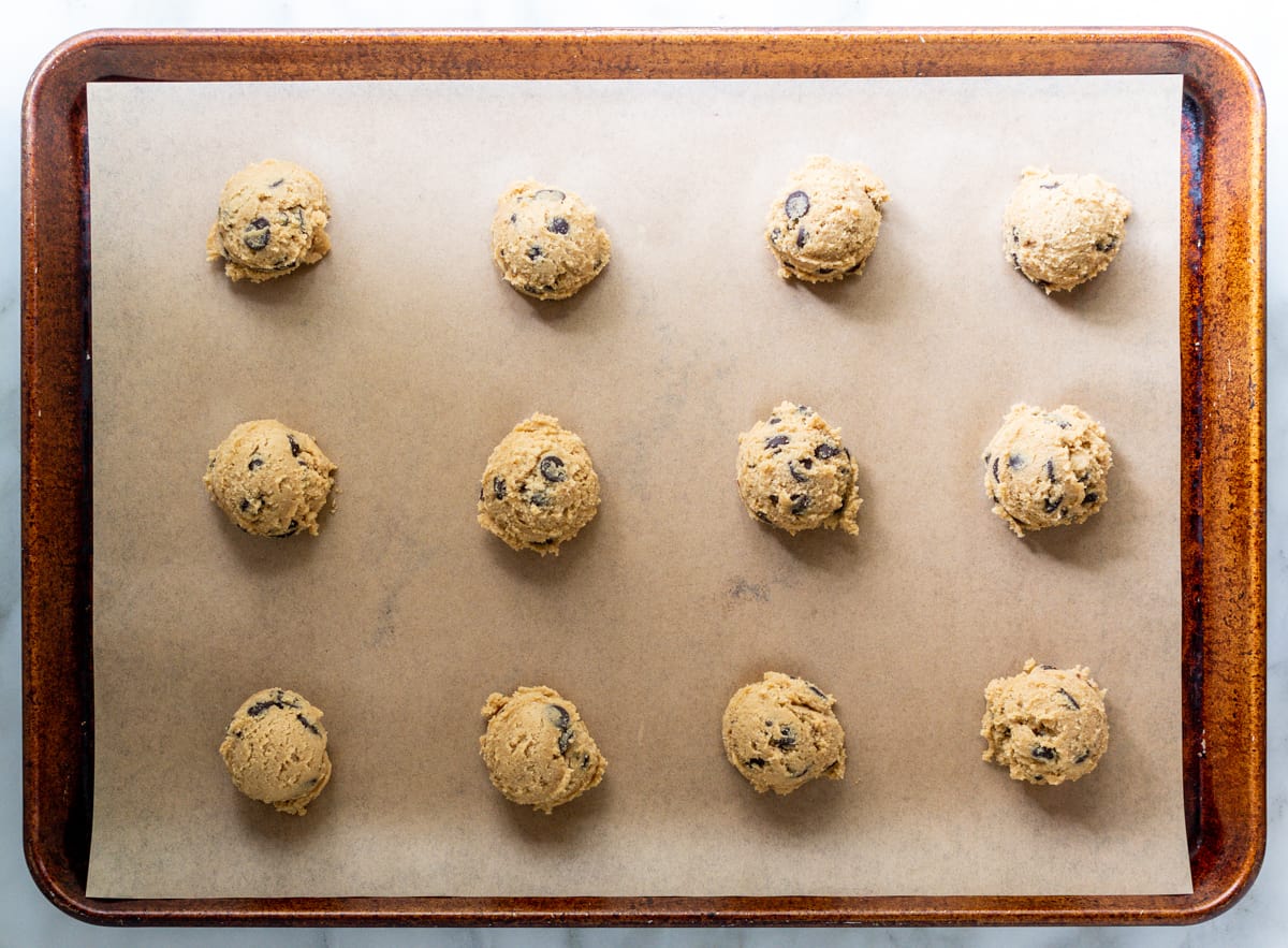 Oat Flour Chocolate Chip Cookie dough scooped onto parchment lined baking sheet.