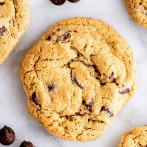 Oat Flour Chocolate Chip Cookies on a white marble board with scattered chocolate chips.