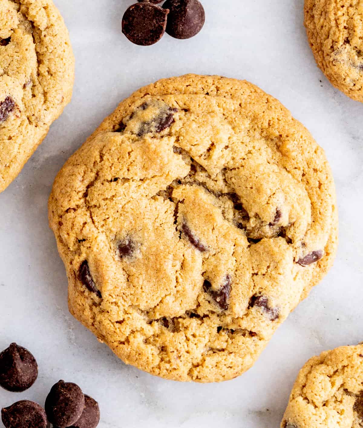 Oat Flour Chocolate Chip Cookies on a white marble board with scattered chocolate chips.