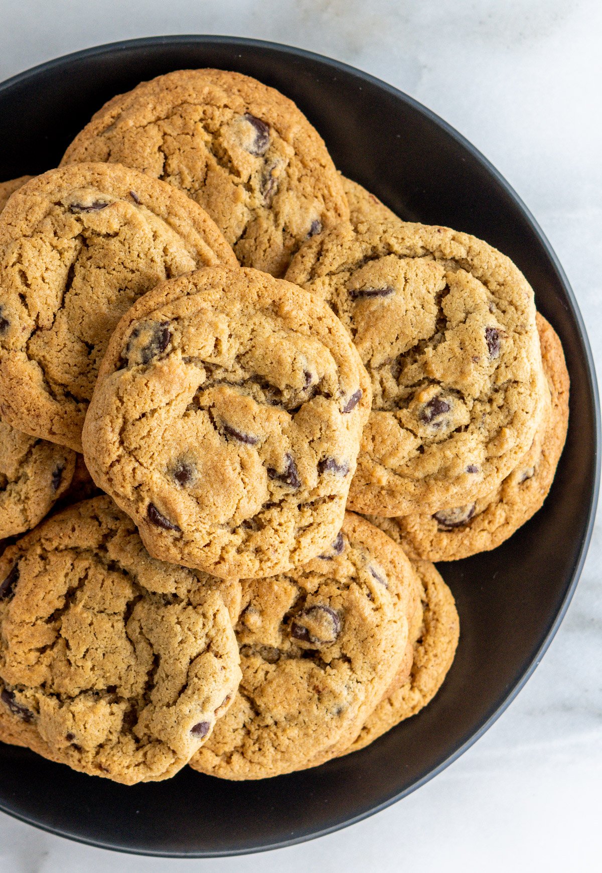 Oat Flour Chocolate Chip Cookies stacked on a black plate and photographed from above.