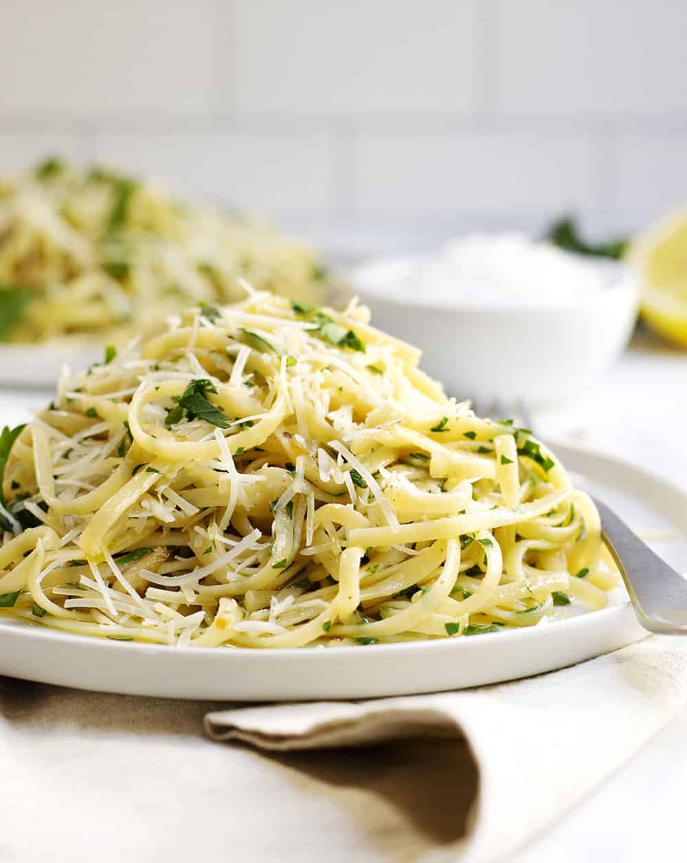 Pasta Aglio e Olio served on white plates with linen napkins