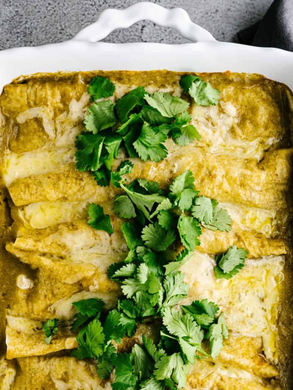 Pulled Pork Enchiladas served in a white ceramic baking dish.