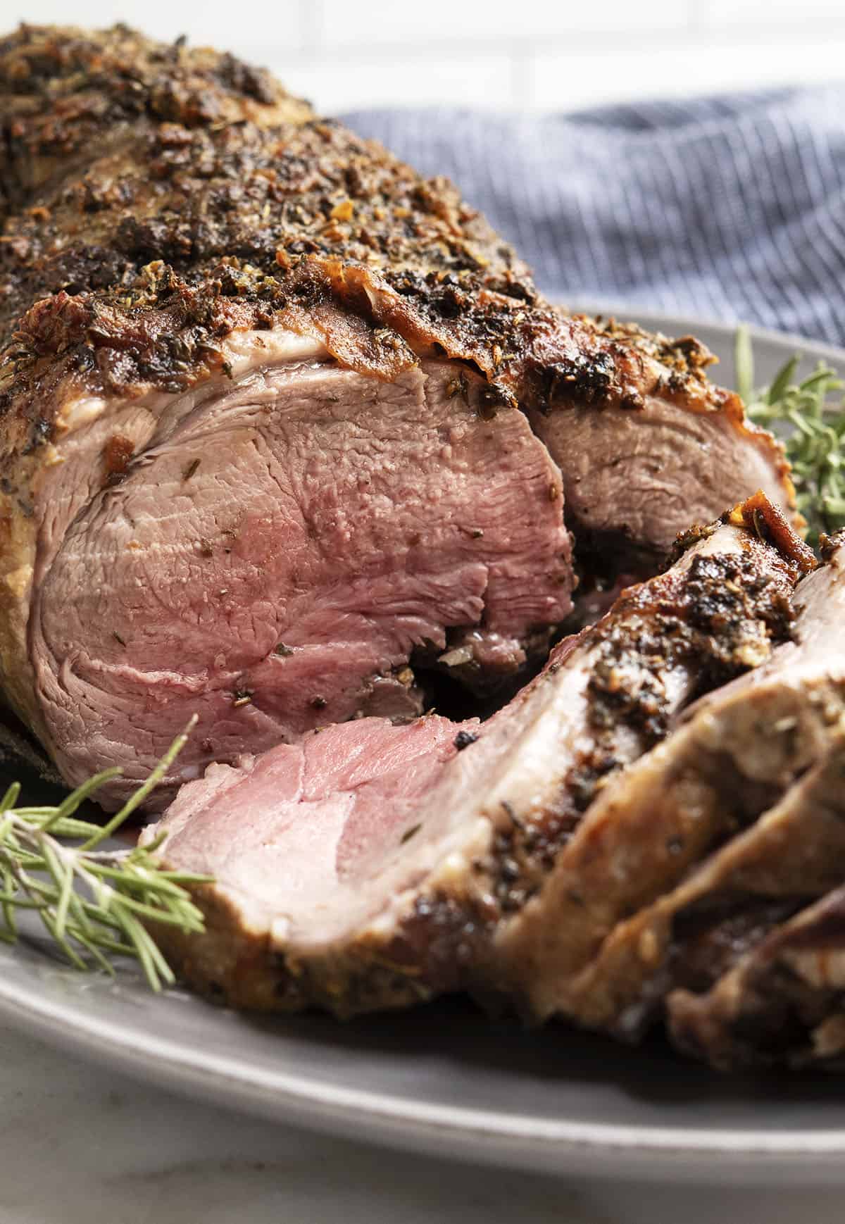 Roasted Boneless Leg of Lamb sliced and served on a gray oval platter