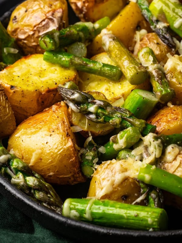 Roasted Potatoes and Asparagus photographed at an angle in a black bowl.