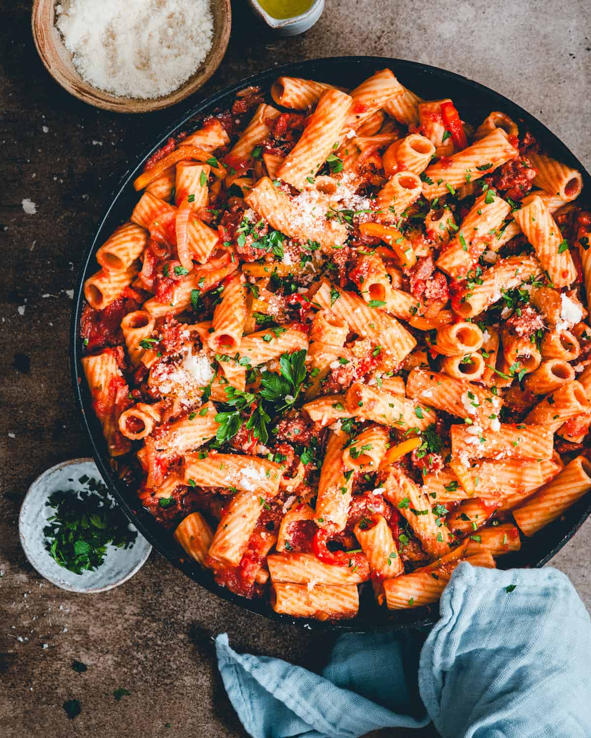 Sausage and Peppers Pasta in a black serving bowl in a moody scene and photographed from the top.