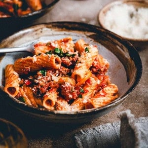 Sausage and Peppers Pasta served in a dark bowl in a moody scene and photographed from an angle.