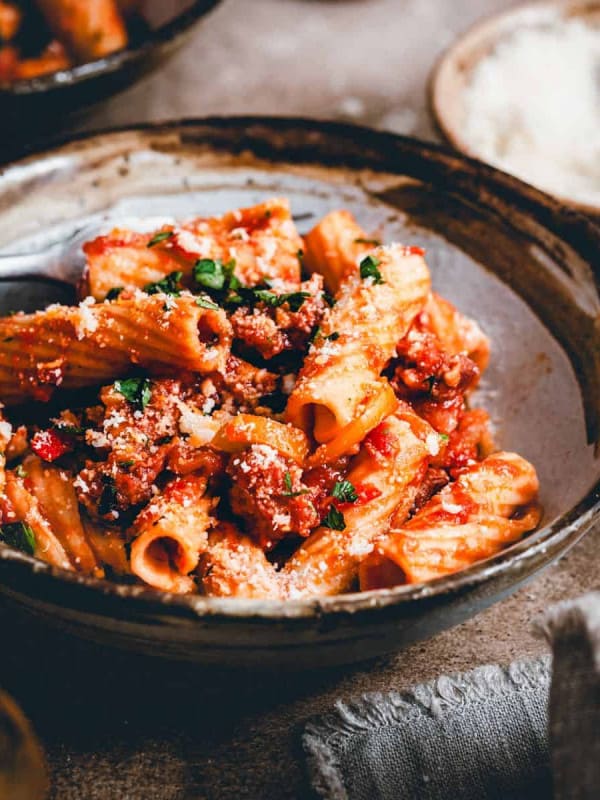 Sausage and Peppers Pasta served in a dark bowl in a moody scene and photographed from an angle.