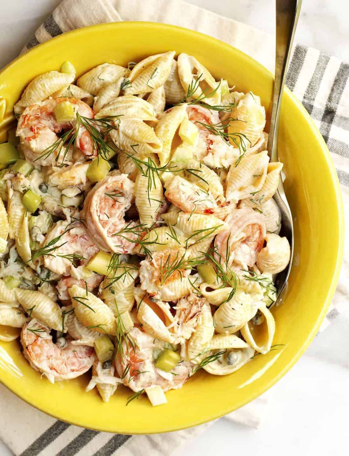 seafood pasta salad served in a yellow ceramic bowl