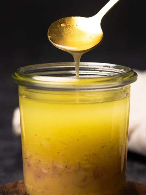 Shallot Vinaigrette in a small jar spooned by a gold spoon.