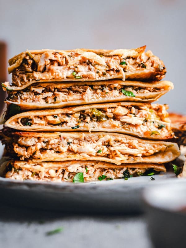 Shredded Chicken Quesadillas stacked on a ceramic plate.